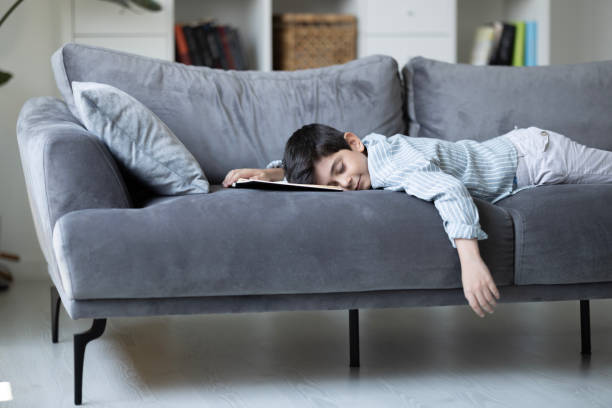istock A cute boy is sleeping on the sofa with a book in his hands 2201123845