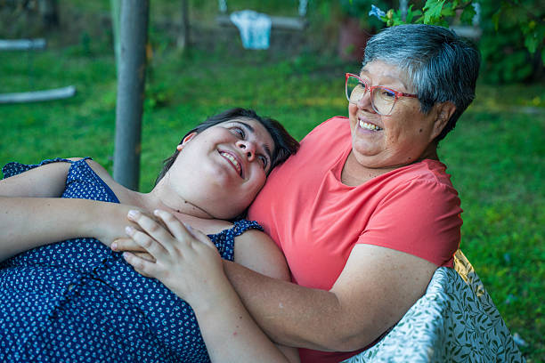 istock Two joyful women are smiling widely and hugging each other on a table 2201124143
