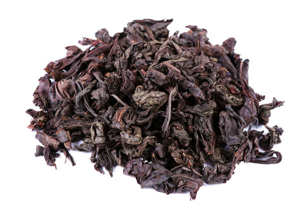 istock dry black tea leaves isolated on white. close up 2201126282