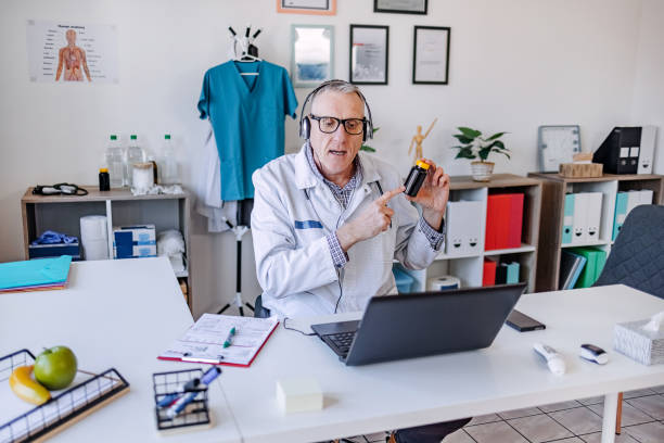istock Male doctor alone in his office having a online meeting using laptop 2201126709