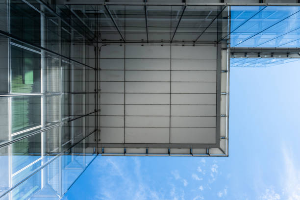 Looking up the glass facade of a large office complex.