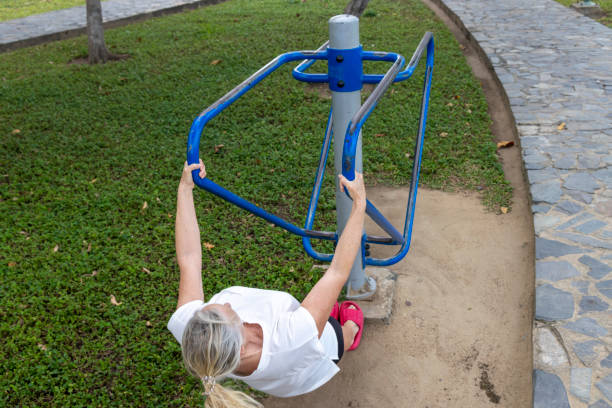 Mature woman  perform exercises in outdoor exercise park in coastal Vietnam