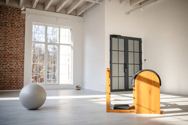 istock Young woman practicing pilates indoors with specialized equipment in a bright, spacious studio 2201129573