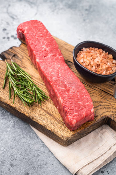istock Juicy raw Kobe style beef, renowned for its exceptional flavor and tenderness. Perfect for preparing mouthwatering steaks or sashimi. grey background. top view 2201130287