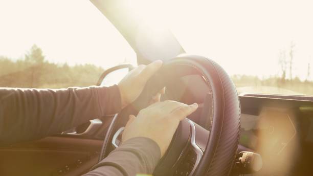 istock A man confidently driving a sleek car under a bright blue sky on a sunny day. 2201131631