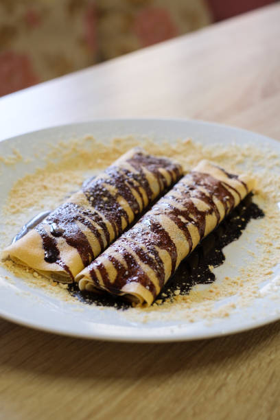 istock Two crepes drizzled with chocolate sauce and sprinkled with crumbs 2201136745