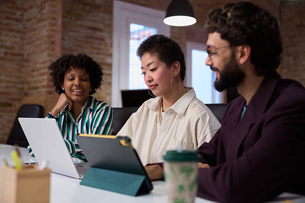 istock Young professionals collaborating on project in modern office using digital tablet and laptop 2201155537