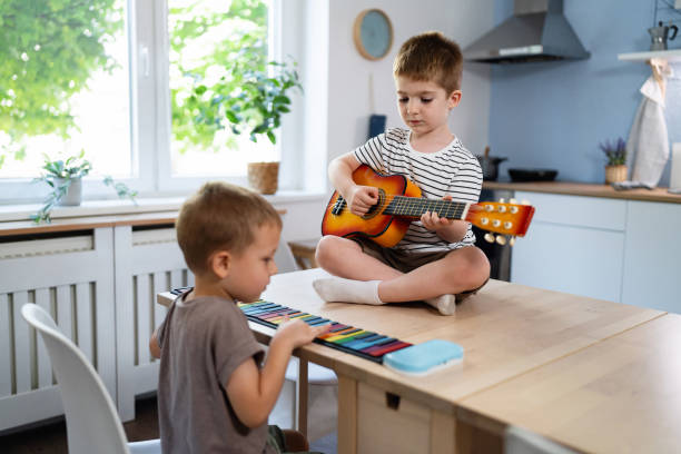 istock Two little brothers playing musical instruments together in a sunlit kitchen 2201156518