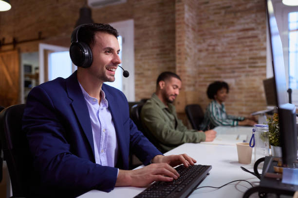 istock Smiling male call center agent working in busy office 2201156520