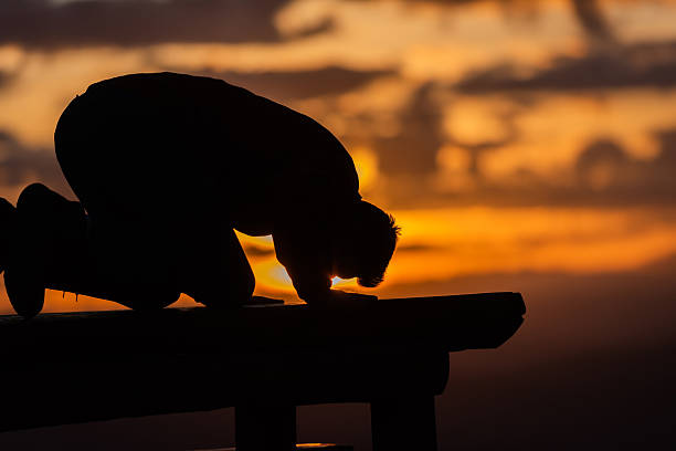 Silhouette of muslim woman prayer having worship and praying with hands open doing dua to Allah at sunset . High quality photo