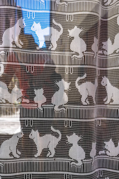 Intricately designed curtain with cat motifs photographed in Mosset, France.