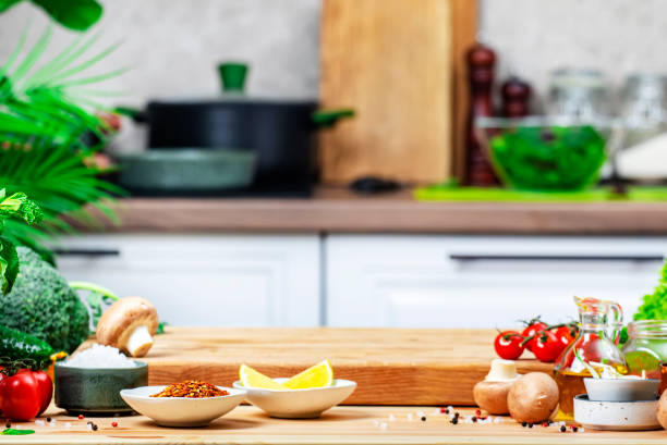 Healthy vegan food, eating, cooking, blogging background. Empty rustic cutting board with mushrooms, tomatoes, lettuce, vegetables on white kitchen with wooden table, kitchenware and utensils.