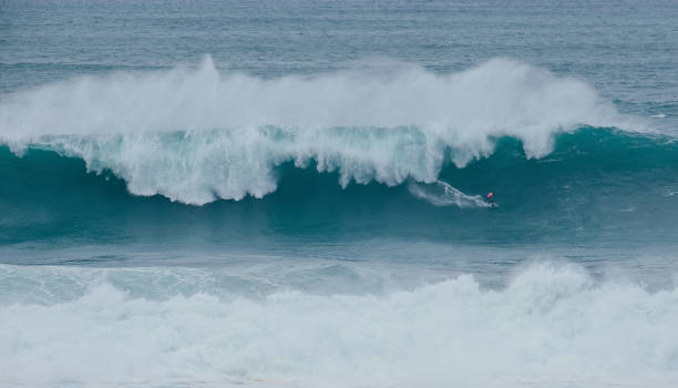 istock Lonely surfer on Huge Atlantic ocean wave during international surfers challenge at Praia do Norte in Nazare, Farol da NazarÃ©, Portugal where Guinness World Record for the highest surfing was set 2201175727