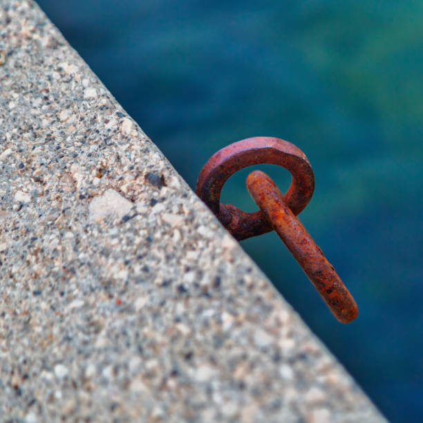 istock Rusty iron mooring ring for boat on concrete pier against sea water background 2201176294
