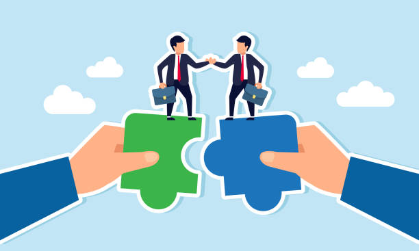 istock Two businessmen stand on a puzzle piece held by hands, agreeing and shaking hands, illustration of an agreement for collaboration in a joint venture 2201179273
