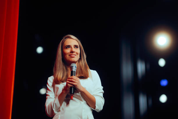 istock Woman in White Blazer Dress Holding Microphone on Stage 2201191738
