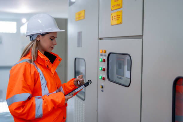 istock Female electrical engineer inspects electrical system at equipment control cabinet High voltage transformers in distribution substations 2201193873