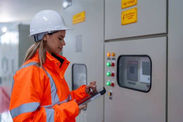 istock Female electrical engineer inspects electrical system at equipment control cabinet High voltage transformers in distribution substations 2201193877