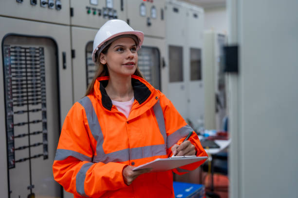 istock Female electrical engineer inspects electrical system at equipment control cabinet High voltage transformers in distribution substations 2201193880