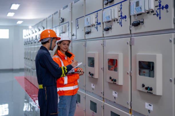 istock Efficient teamwork in industrial setting, showcasing man and woman discussing electrical equipment in safety gear. Their focus highlights importance of safety and collaboration 2201193936