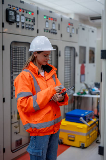 istock Female electrical engineer inspects electrical system at equipment control cabinet High voltage transformers in distribution substations 2201193955