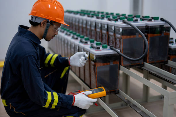 istock technician in orange helmet tests battery systems with multimeter, ensuring safety and efficiency in modern facility 2201193998