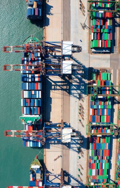 istock Vertical top down view of cargo containers piled on the quayside and cranes unloading the goods from a ship, which is parking at the dock of Taipei Harbor in Bali District, New Taipei City, Taiwan 2201201175