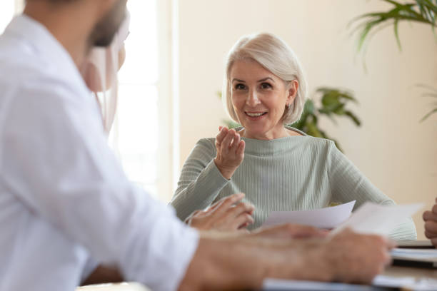istock Middle-aged businesswoman ask question to participant during group meeting 2201215193