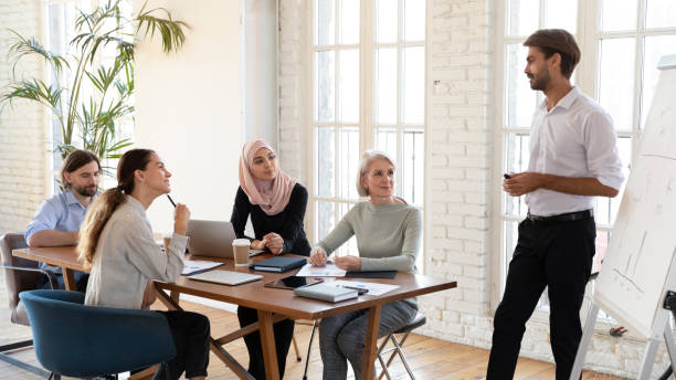 istock Confident businessman makes presentation on flipchart for multicultural investors 2201217306