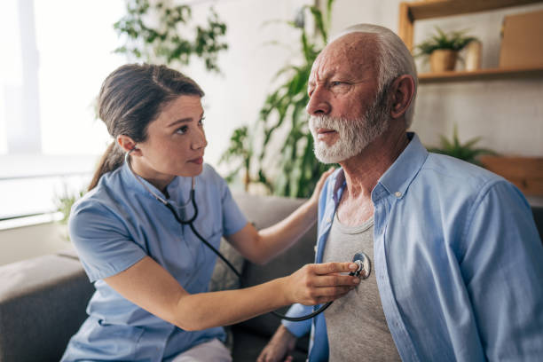 istock Female nurse examining senior man with stethoscope at home 2201217969