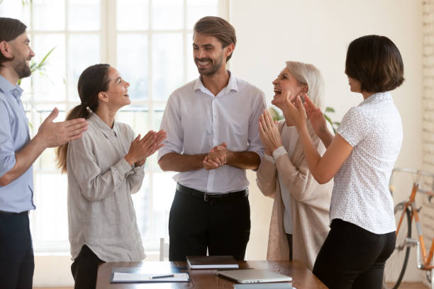 istock Five workmates standing in boardroom applauding congratulating team leader 2201218797