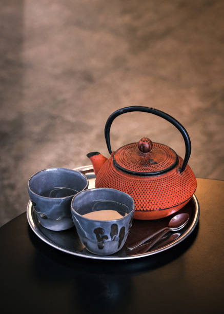 Traditional Japanese cast iron teapot with two ceramic tea cups on a metal tray, cozy tea ceremony and Asian tea culture concept