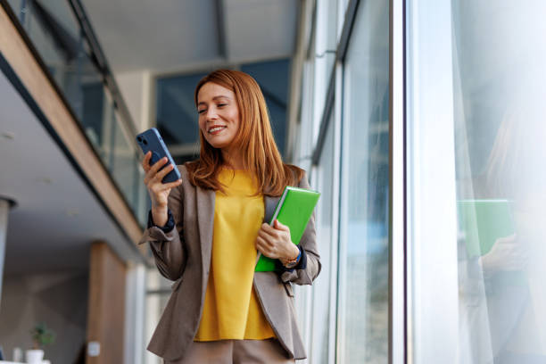 istock Businesswoman using smartphone and holding notebooks in modern office 2201222198