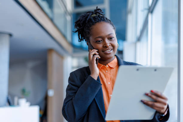 istock Young manager talking on the phone and reading documents in modern office 2201222265