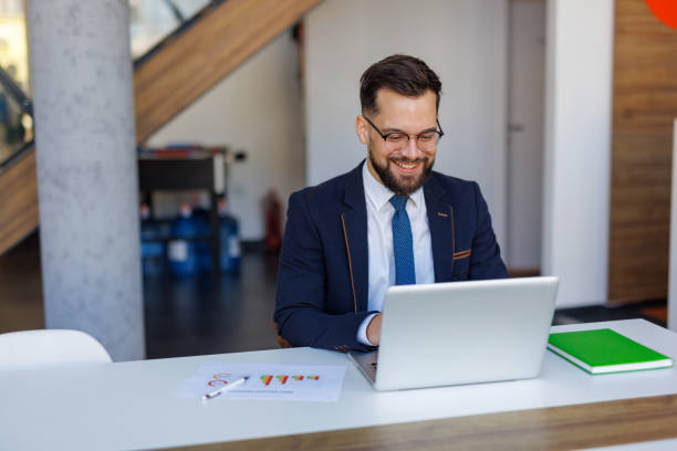 istock Businessman working on laptop in modern office analyzing graphs 2201222453