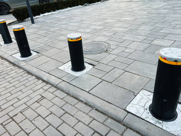 istock Black retractable bollards aligned on paved urban pathway with manhole cover 2201228248