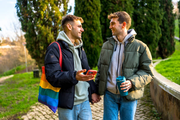 istock Gay couple holding hands and walking in a park 2201231604