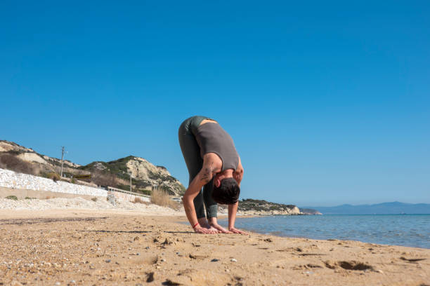 istock Attractive middle-aged woman practicing yoga on a beautiful beach 2201232849