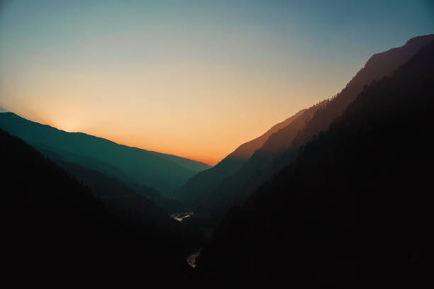 This breathtaking image captures a mesmerizing sunset over a remote village in the Har Ki Dun Valley, nestled in the Indian Himalayas. As the sun sets behind the rugged mountain peaks, the valley is bathed in hues of orange and deep blue, creating a serene and mystical ambiance. A winding river glimmers in the fading light, enhancing the untouched beauty of this Himalayan paradise. Known for its scenic trails and traditional mountain settlements, Har Ki Dun offers an enchanting retreat for trekkers and nature lovers seeking solitude in the lap of nature.