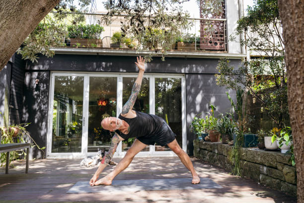 istock Senior man with tattoos practising yoga in garden, triangle pose 2201239375