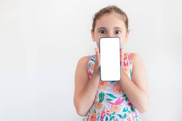 Smiling girl shows a blank screen smart phone on white background