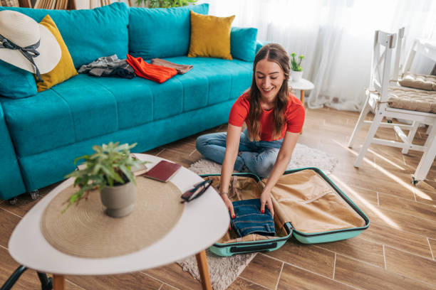 istock Young woman packing clothes into suitcase at home getting ready for summer vacation 2201240526