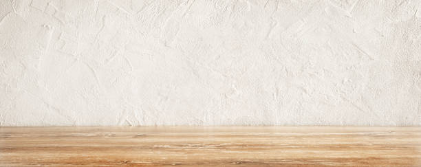 istock Rustic wooden table surface with a textured white wall background in a well-lit kitchen 2201241862