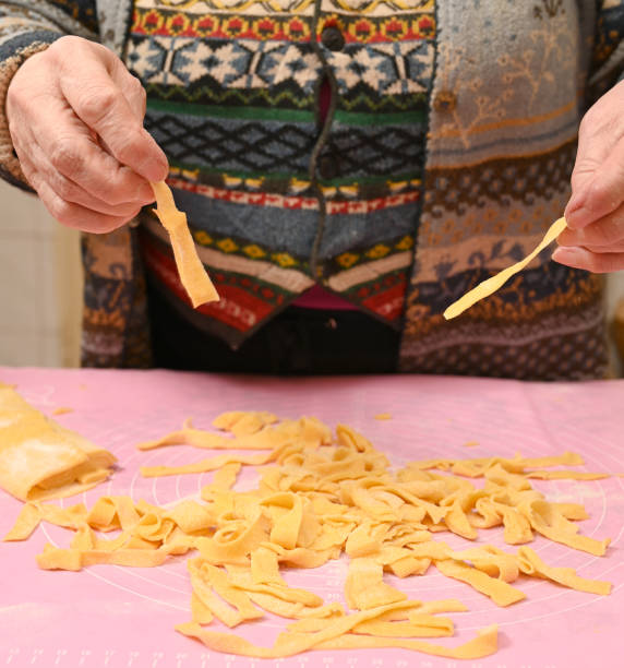 istock Woman skillfully shaping and cutting fresh pasta in a warm kitchen environment 2201244746