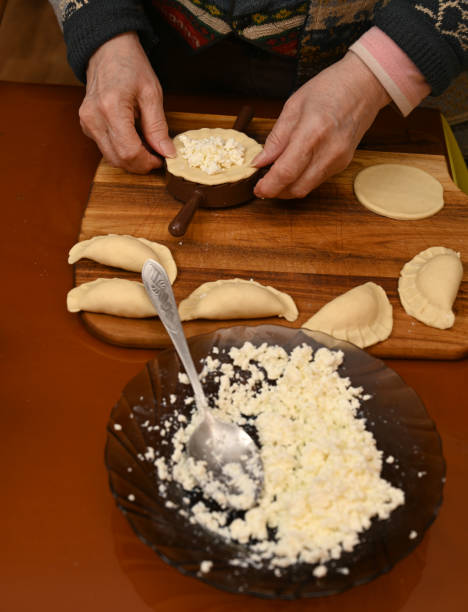 istock Woman skillfully fills dough circles with cheese in a warm kitchen 2201244921
