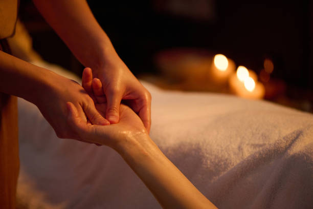 Medium close up of unrecognizable female hands using essential oil to do deep massage