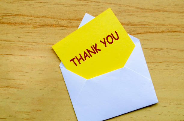 istock White envelope on a wooden surface with a yellow card partially pulled out with Thank You text 2201263568