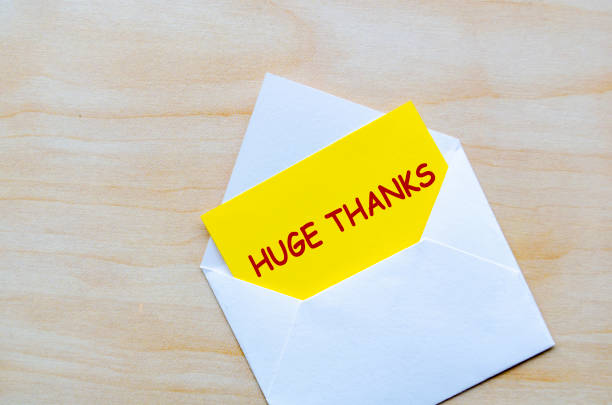White envelope on a wooden surface with a yellow card partially pulled out with Huge Thanks text