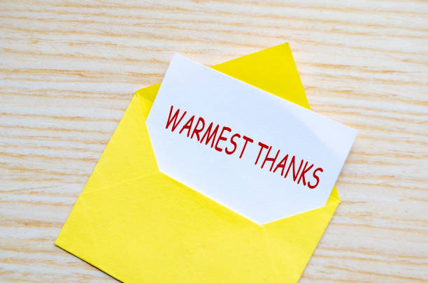 istock Top view of yellow envelope on a wooden surface with a white card partially pulled out with text Warmest Thanks 2201263716