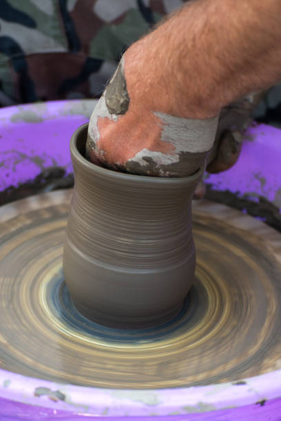 Hands of a potter, creating an earthen jar on the circle.